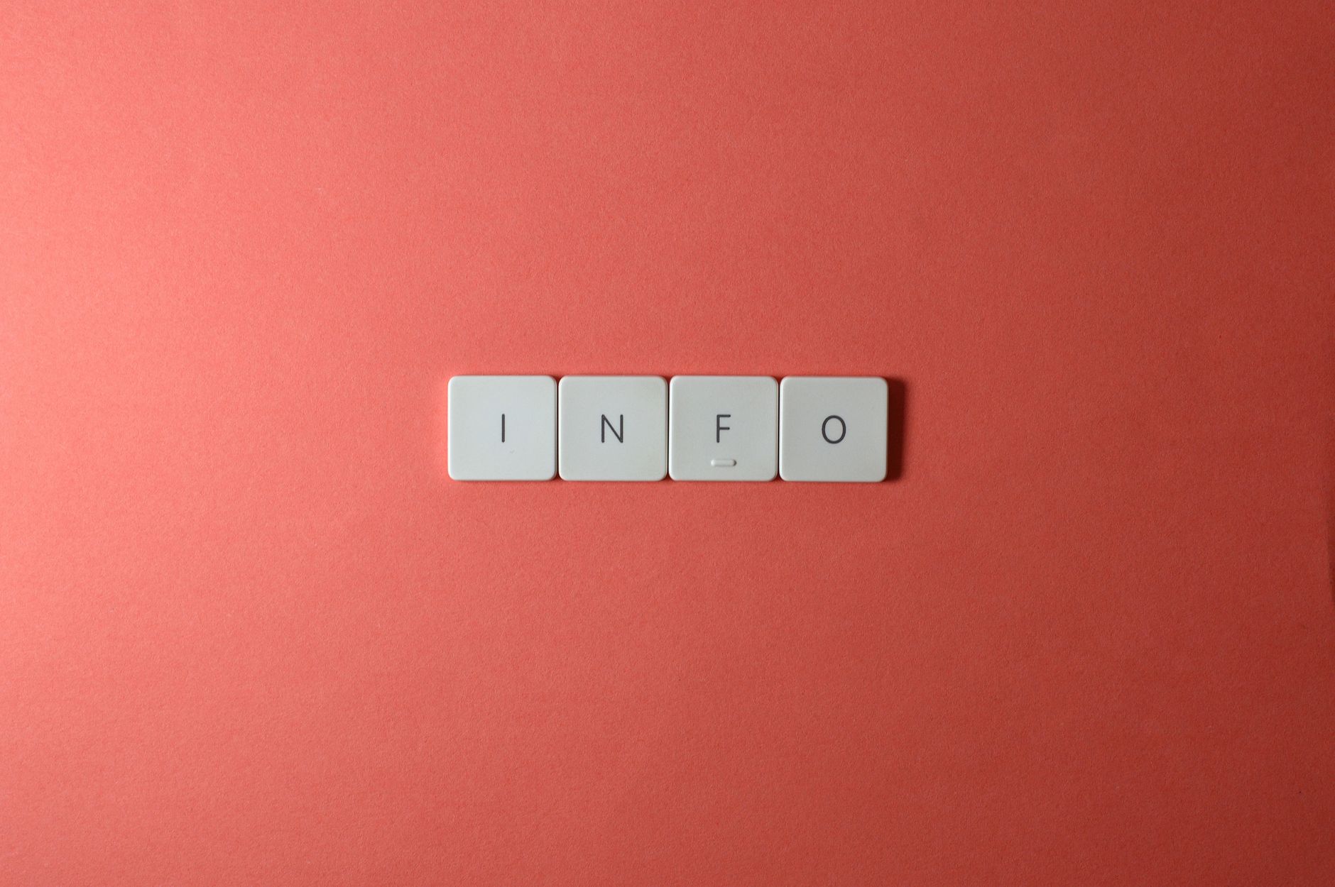 Close-up of keyboard buttons spelling 'INFO' on a minimal red background
